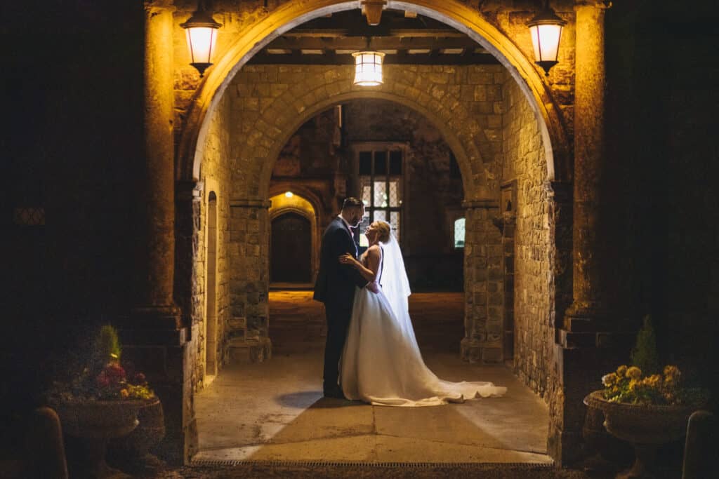 bride and groom in an archway at night at Eastwell Manor