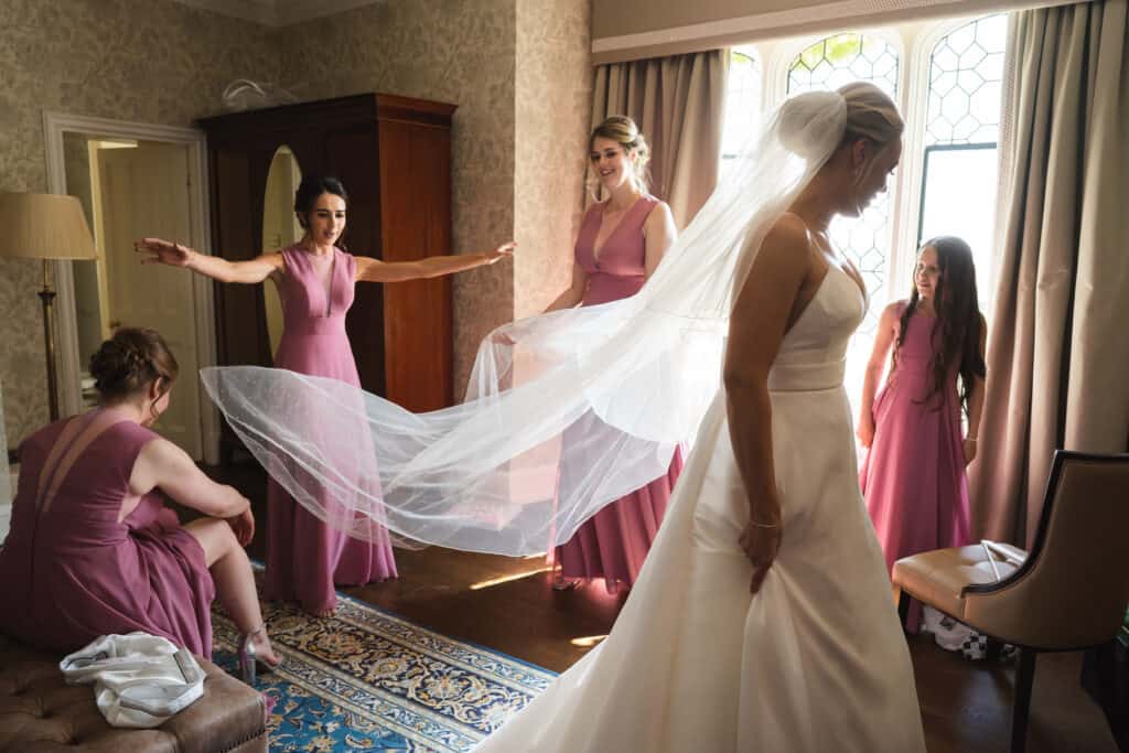bride in dress with bridesmaids in room before wedding