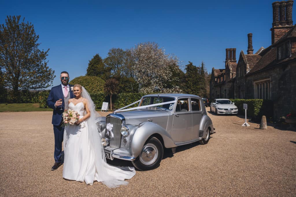 Bride and groom in front of their Bentley wedding car
