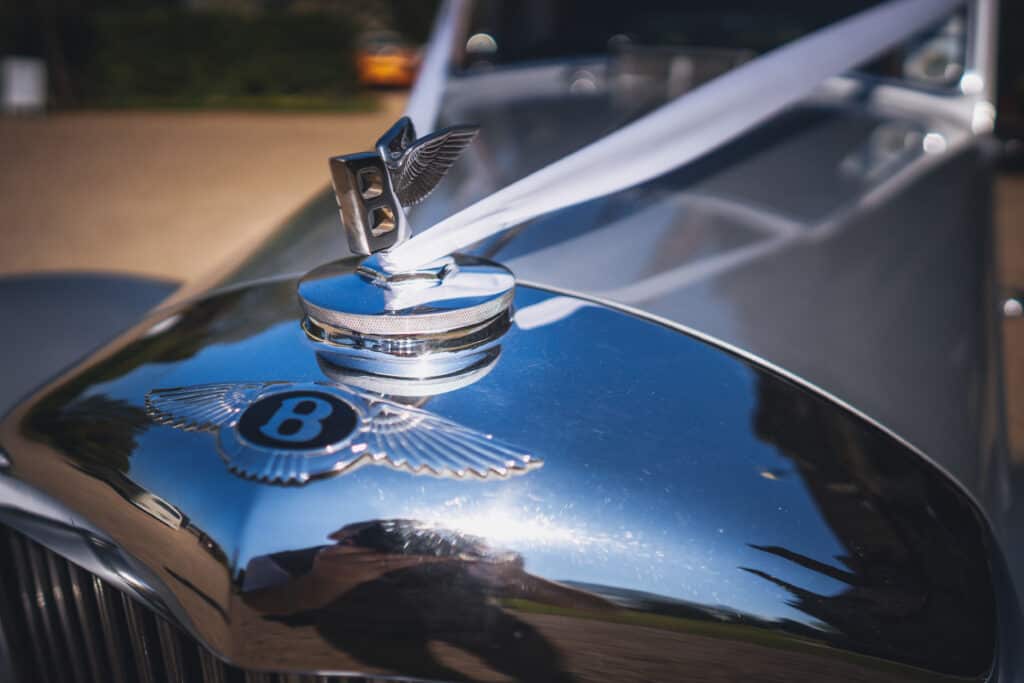 Silver Bentley wedding car decorated with ribbon