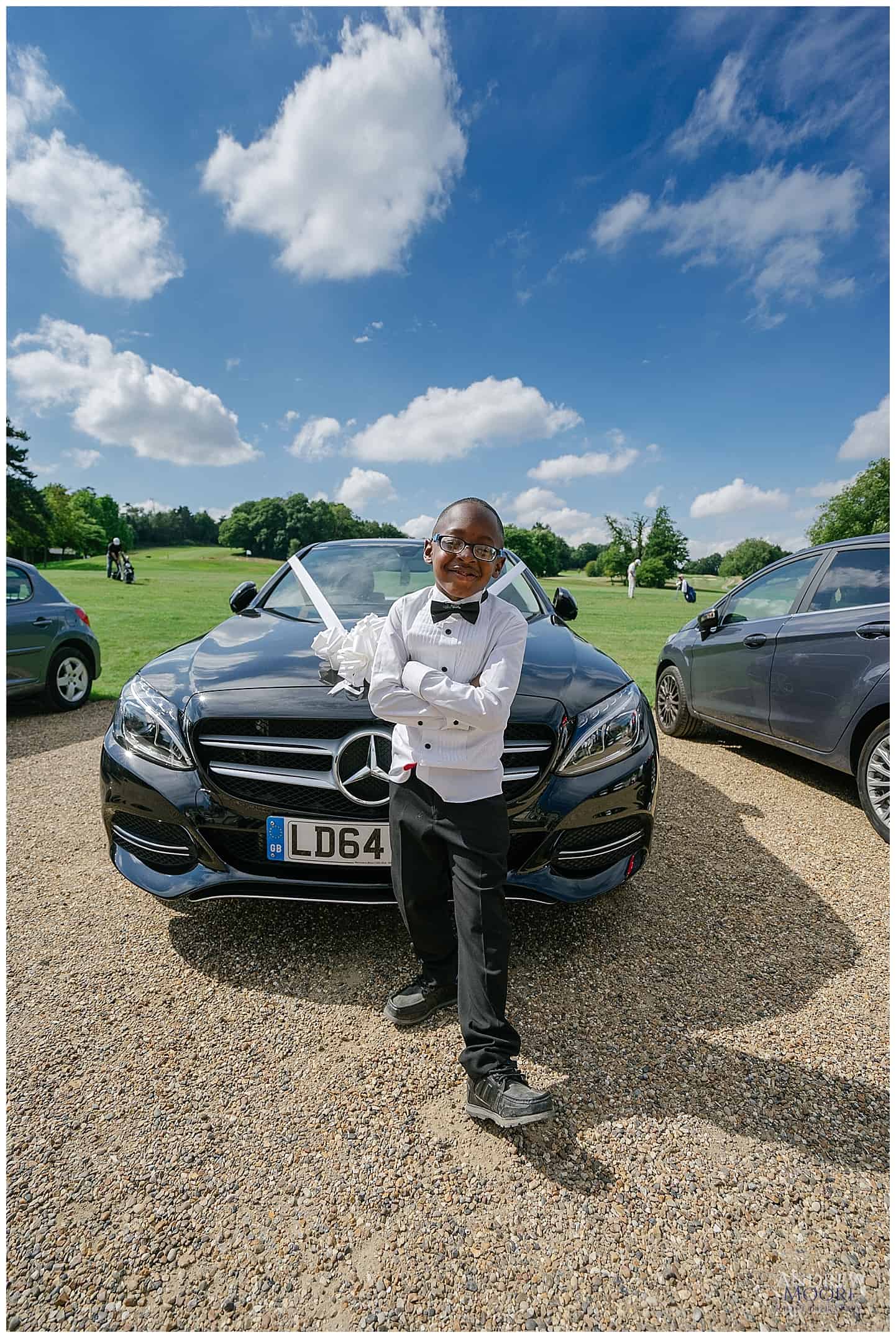 young page boy in front of car wide angle 